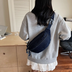Détail du sac à bandoulière en denim bleu avec fermetures éclair et sangle réglable