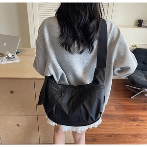 Close-up of black nylon crescent dumpling bag featuring multiple zip pockets and wide strap