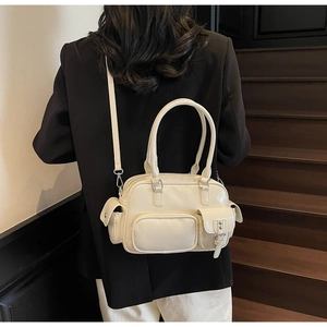 Detailansicht der praktischen Mehrfachtaschen und silbernen Beschläge der elfenbeinfarbenen Tasche