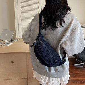Détail du sac bandoulière en denim bleu avec double fermeture éclair et sangle réglable