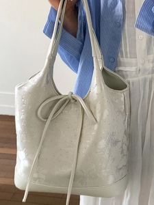 Minimalist beige floral tote bag with silver studs and lace-up bow detail for women