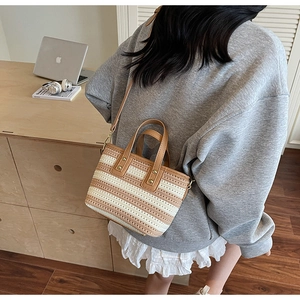 Detailed view of striped woven straw bag with leather handles shown in a lifestyle setting