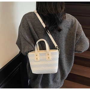 Detail of white woven bucket bag featuring gold rivets and elegant textured finish