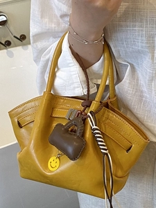 Minimalist yellow leather tote bag with brown mini-pouch charm and silver buckle detail
