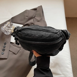 Détail d'un sac bandoulière en jean noir avec nœud latéral et poches zippées