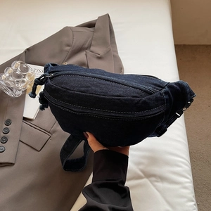 Vue détaillée du sac banane en denim bleu foncé avec plusieurs fermetures éclair et texture