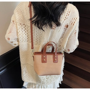 Straw bucket bag detail with brown leather trim and gold studs on beige woven texture