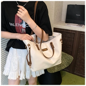 Detail of white PU leather tote bag with brown straps and golden metallic hardware