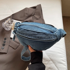 Détail d'un sac bandoulière en denim bleu délavé avec fermetures éclair noires