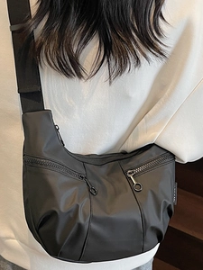 Minimalist black nylon dumpling crossbody bag with multiple pockets and ring zippers