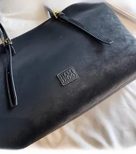 Détail du cabas noir mat HAM IROO avec logo embossé et bandoulière en cuir souple