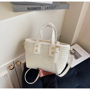 Detail of woven straw bucket bag with white leather trim and gold rivets