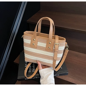 Detail view of woven straw bucket bag with striped pattern and gold rivet accents