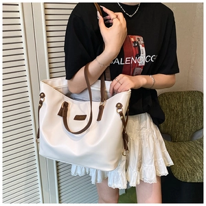 Detail view of large white tote bag with contrast brown straps and gold metal hardware