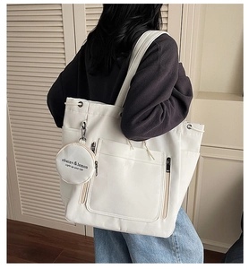 Detail view of large white canvas tote bag with side pockets and a mini hanging pouch