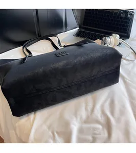 Macro d'un grand sac fourre-tout noir avec de longues anses sur une literie blanche