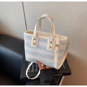 Detailed view of a blue and white striped woven bucket bag with leather handles and gold hardware