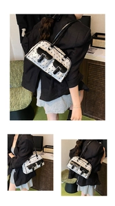 Detail of white pleated handbag featuring black bow embroidery and leather buckled pockets