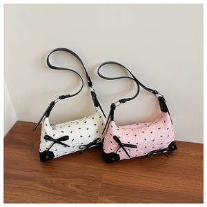 Detail of pink and white shoulder bags with embossed pattern and black bow accents
