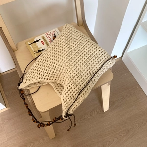 Détail du sac cabas au crochet beige avec motif résille et bandoulière en perles de bois
