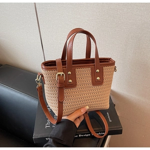 Detail of straw woven bucket bag with brown leather straps and gold metal rivets
