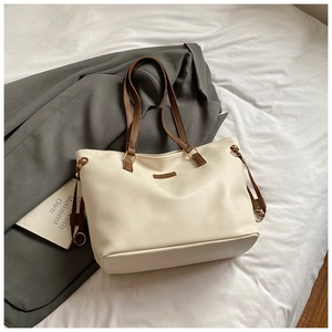 Detail view of cream PU leather tote bag with contrasting dark brown shoulder straps