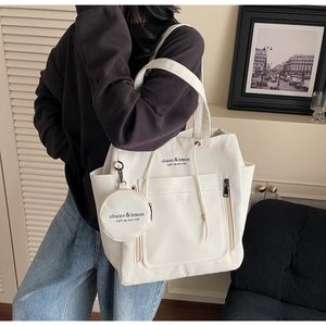 Detail of white canvas tote bag with side vertical zipper and small round charm pouch