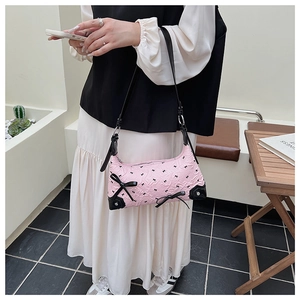 Detail of pink shoulder bag with black bow prints and 3D ribbon accents on the front