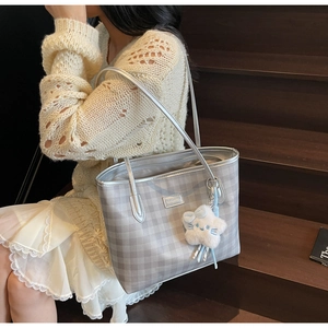 Detail of silver checkered tote bag with plush star charm on wooden stairs background