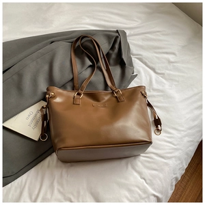 Detail of matte brown faux leather tote bag with adjustable drawstrings and metal rings