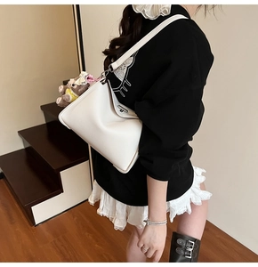 Detail of white litchi pattern leather shoulder bag with cute brown plush bear charm