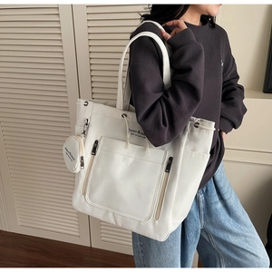 Close-up of white canvas tote bag with drawstring closure and mini round coin pouch charm