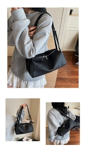 Detail view of the black textured leather shoulder bag showing the dual zipper and straps