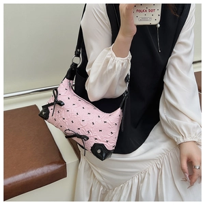 Detail of pink and black textured shoulder bag with bow and metal rivet decorations