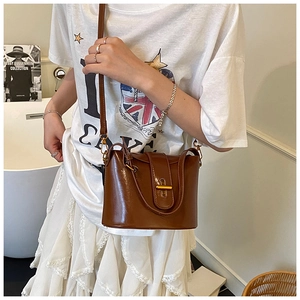 Detail einer dunkelbraunen Vintage-Leder-Eimertasche mit goldenem Metall-Drehverschluss