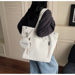 Detail view of large white canvas tote bag with round coin purse and drawstring feature