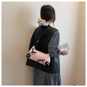 Close-up of pink hobo bag with black bow details and reinforced leather corners