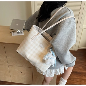 Detail of checkered tote bag with blue bow star pendant on a female model shoulder