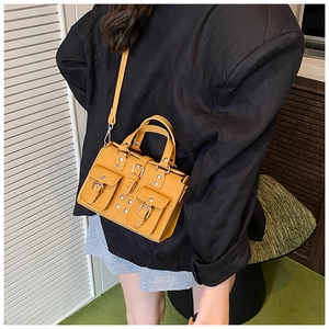 Détail du mini sac Boston jaune avec poches à rabat et décorations de clous métalliques