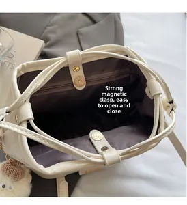 Detail of cream bucket bag showing magnetic closure and interior zipper pocket