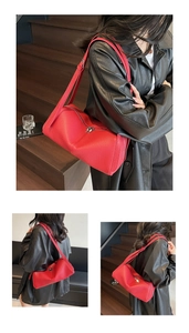 Detail view of red leather cylinder shoulder bag with lychee texture and dual zippers