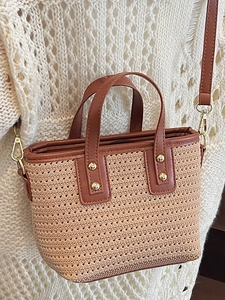 Bohemian straw bucket bag with brown leather trim and golden rivets for beach vacation