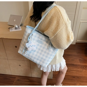 Detail view of light blue checkerboard tote bag with cute plush star charm and logo