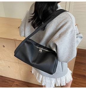 Model wearing a black lychee texture leather shoulder bag with silver double zippers