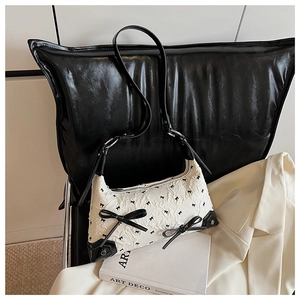 Close-up of the embossed floral texture and black bow decorations on this stylish shoulder bag