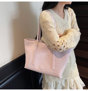 Gros plan d'un cabas en cuir rose avec logo porté par un mannequin en tenue décontractée
