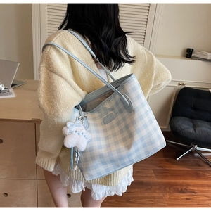 Detail of blue checkerboard tote bag with cute plush cat charm for daily use