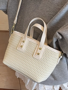 Chic cream straw bucket bag with gold studs and leather trim for summer beach vacations