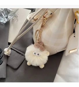 Süßer Plüsch-Schlüsselanhänger mit Strickmütze und Cartoon-Augen an einer Beuteltasche