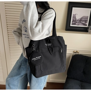 Detailed view of a black canvas tote bag with a round coin purse and drawstring design
